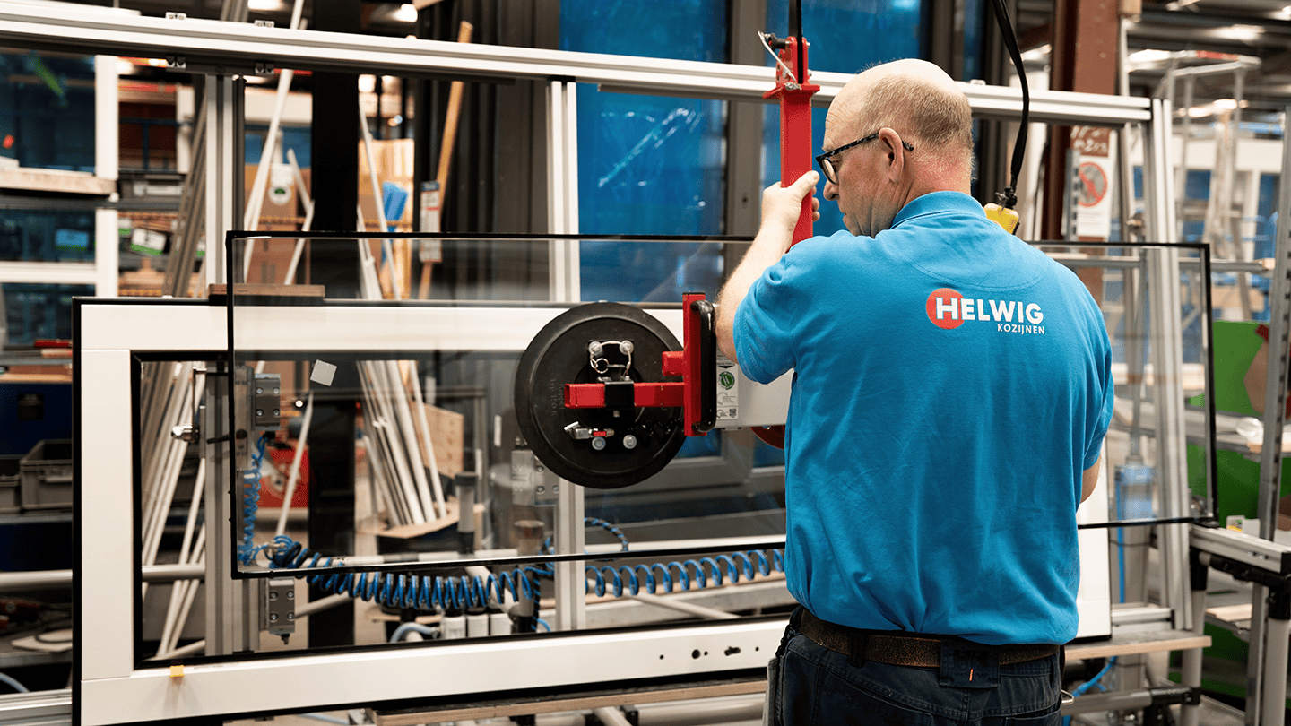 Helwig Mitarbeiter setzt Fensterglas in Holzrahmen.