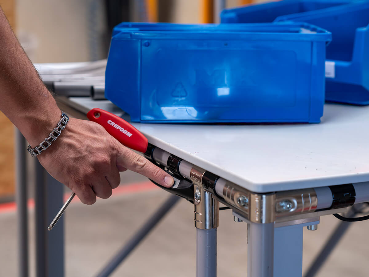 Mitarbeiter verstellt einen höhenverstellbaren Arbeitstisch auf Knopfdruck