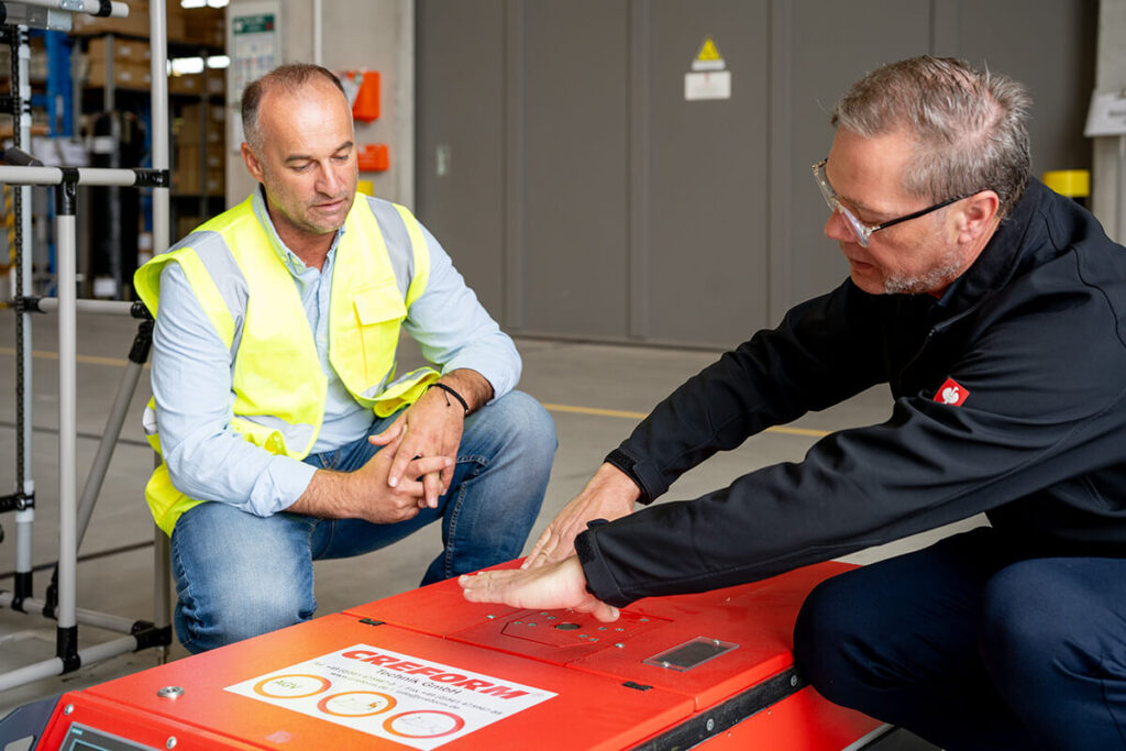 Einem Kunden wird die Funktion an einem FTS Transportwagen erklärt